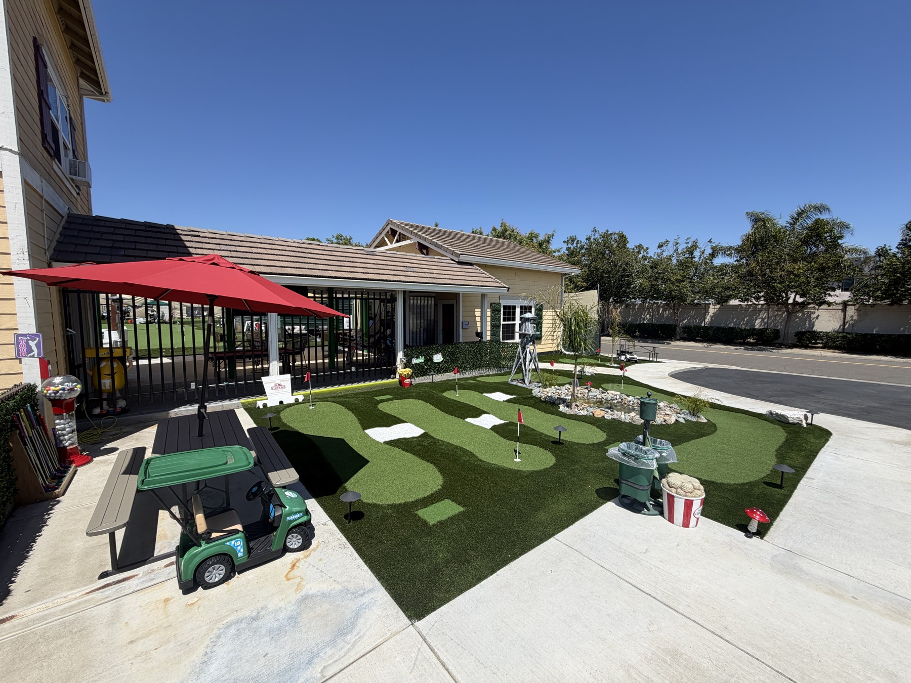 Nine-hole mini golf course out front with flags, a rock water feature and a shaded picnic table
