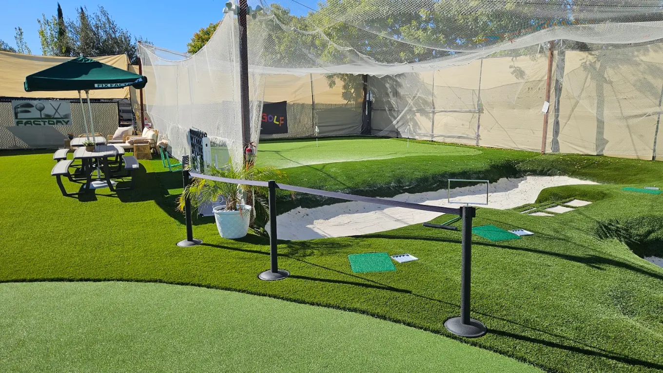 Outdoor short-game area with putting green, chipping targets and a wide white sand bunker